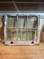 Front view of six-pane wooden window frame showing aged glass and broken pane