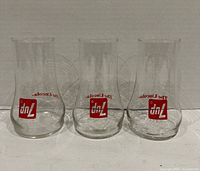 Three clear 7-Up branded glasses standing side by side