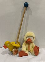 Wooden push duck toy and plush bear in duck costume side by side