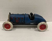 Left side view of blue cast iron race car showing number 6, wheels and driver