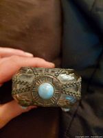 Side view showing ornate metal overlay and central turquoise cabochon on amber glass bottle