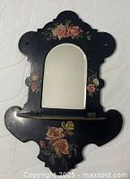 Frontal view showing mirror, floral decoration, shelf folded down