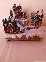 Front view showing three illuminated houses, bridge and trees