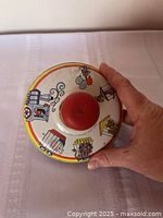 Top view of tin spinning top showing circus lithograph and red knob