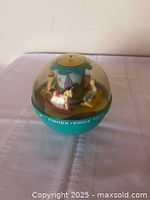 Front view showing clear dome, turquoise base, internal carousel figures