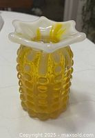 Front view of amber hobnail vase showing raised oval texture and ruffled white opalescent rim