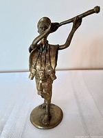 Front view of brass musician figurine with long horn