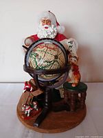Front view of Santa figurine showing globe, cat on stool, toy sack
