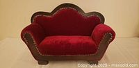 Front view of red velvet miniature loveseat with scalloped back and nailhead trim