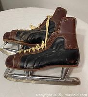 Side view of both skates showing leather uppers, laces, and blades