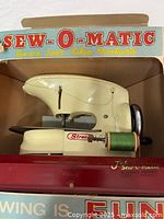 Toy sewing machine inside open front of original box