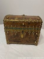 Front view of studded leather chest showing lock, brass studs, and leather surface