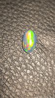 Top view of oval opal showing green and orange play of colour