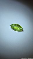 Marquise-cut apple green peridot resting on surface