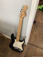 Full view of Fender Starcaster guitar leaning against wall