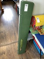 Full view of closed green hard gun case on floor