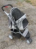 Right side view of gray pet stroller showing mesh canopy, frame, wheels, and storage basket