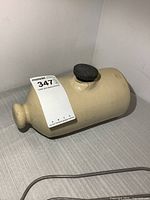 Side view of stoneware foot warmer showing cap and overall shape