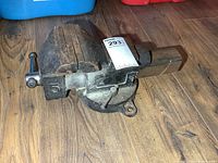 Right side view of cast iron bench vise on wood floor, mounting base and jaw faces visible