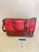 Front view of red and brown croc-embossed Brahmin satchel with strap attached
