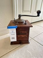 Three-quarter view showing full grinder with crank extended and lot tag