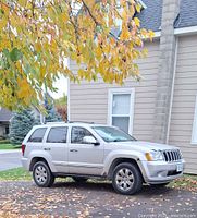 Front passenger side view of silver Jeep Grand Cherokee parked outdoors