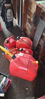 Five red plastic fuel cans grouped together showing sizes and spouts