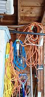 Assorted orange, blue and yellow extension cords hanging, plus power strip in workshop setting