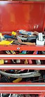 Top view of red tool chest with mixed screwdrivers, chisels, sockets and other small tools