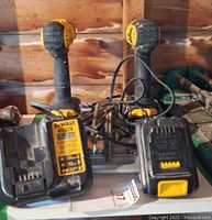 Two DeWALT drill/drivers, DCB107 charger, batteries, cords visible on shelf