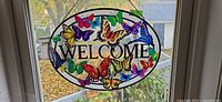 Full view of oval butterfly welcome suncatcher hanging in window