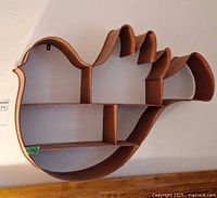 Full view of bird-shaped metal wall shelf on wall