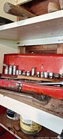 Toolbox on shelf with sockets on upper tray and ratchet in lower compartment