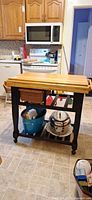 Full view of cart showing butcher-block top, basket drawer, lower shelf and casters