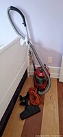 Complete vacuum setup leaning against wall with hose, wand, floor head, and extension cord visible