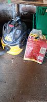 Full view of Shop-Vac canister vacuum with hose and accessory bag beside it