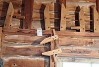 Row of five large wooden screw clamps hanging on wall with one small clamp leaning