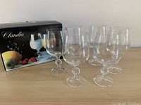 Six crystal goblets arranged in front of original Claudia box