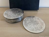 Stack of eight round silver-plated placemats, tarnish visible