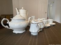 Full view of coffee pot, teapot, sugar bowl, cups and saucers