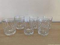 Six crystal tumblers on wooden surface