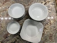 Stacks of soup bowls, dessert plates and one rice dish displayed on countertop