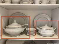 Two white porcelain soup tureens with lids and stack of small plates (plates not included)