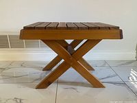 Side view of wooden slat table showing X-frame legs and slatted top