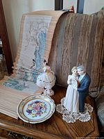 Group shot showing both figurines, floral plate on stand, crochet doily and bamboo scroll