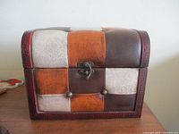Front view of leather patchwork humpback trunk with brass latch and studs
