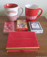 Lot overview showing two Baileys mugs, three visible sealed card decks and red velvet box