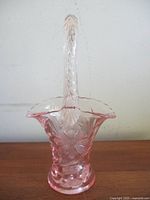 Front view of pink depression glass basket showing handle and cornflower pattern