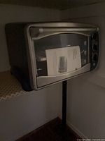 Front view of toaster oven showing stainless door, handle, knobs and manual inside