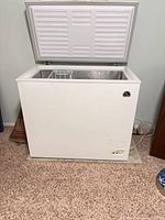 Overall view of white chest freezer opened showing interior and basket